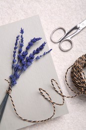 Photo of Preserved lavender flowers, scissors, twine and notebook on white textured table, flat lay