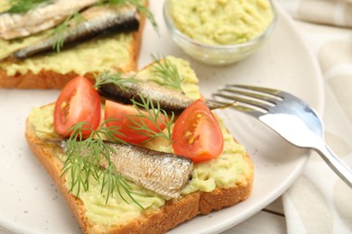Photo of Delicious sandwiches with sprats, tomatoes, dill and avocado puree served on white table, closeup