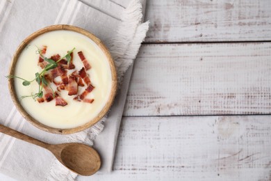 Delicious potato soup with bacon and microgreens in bowl served on wooden table, flat lay. Space for text