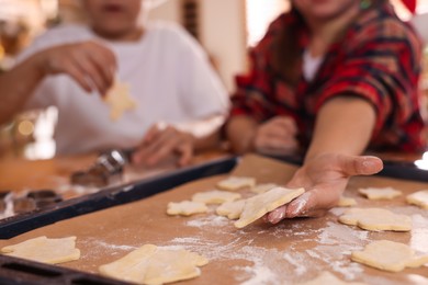 Photo of Cute little children making delicious Christmas cookies at home, closeup