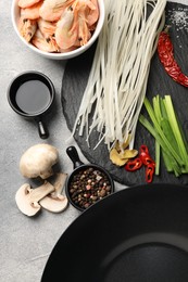 Photo of Flat lay composition with black wok, spices and products on grey textured table