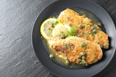 Photo of Delicious chicken piccata on black table, top view