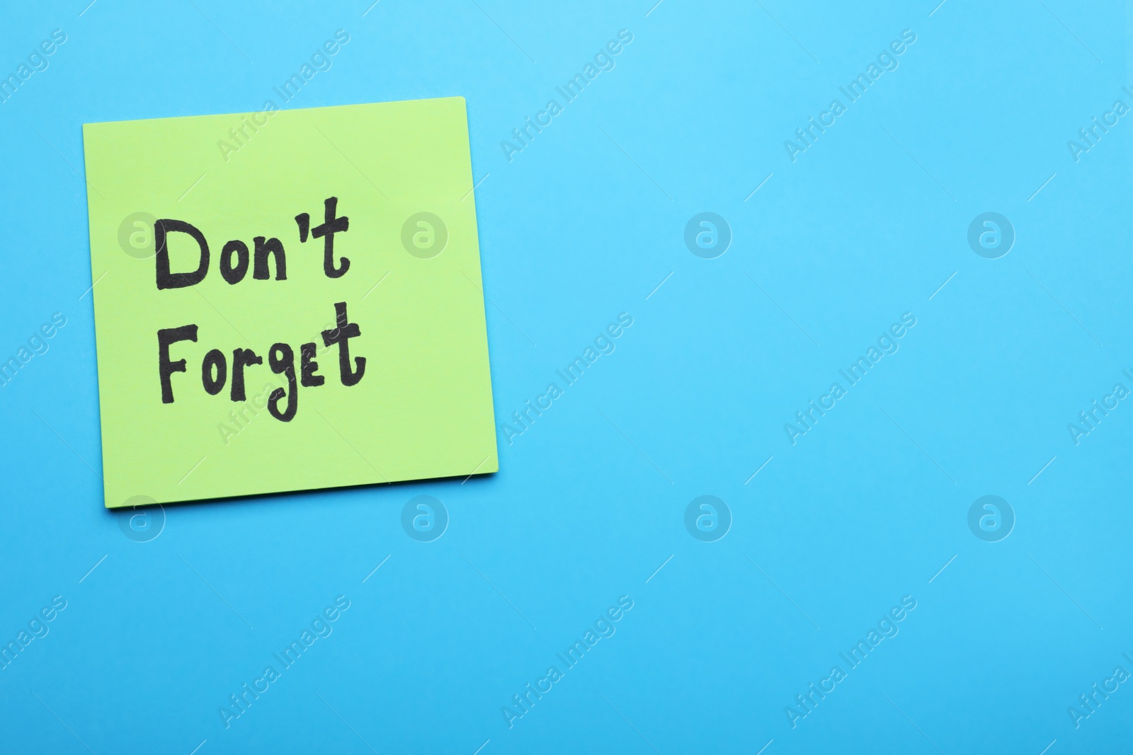 Photo of Paper note with phrase Don' t Forget on blue background, top view. Space for text