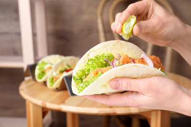 Photo of Woman squeezing lime on fish taco indoors, closeup