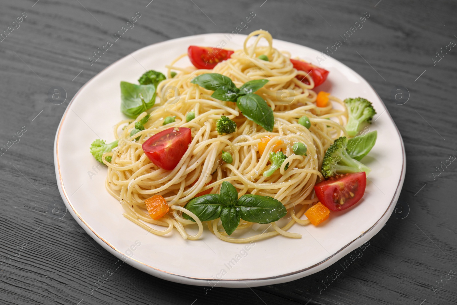 Photo of Delicious pasta primavera with tomatoes, basil and broccoli on grey table, closeup