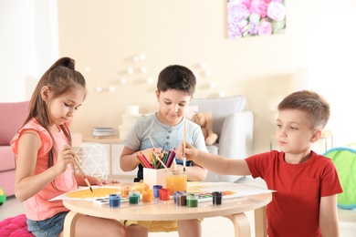 Photo of Cute little children painting at table in playing room