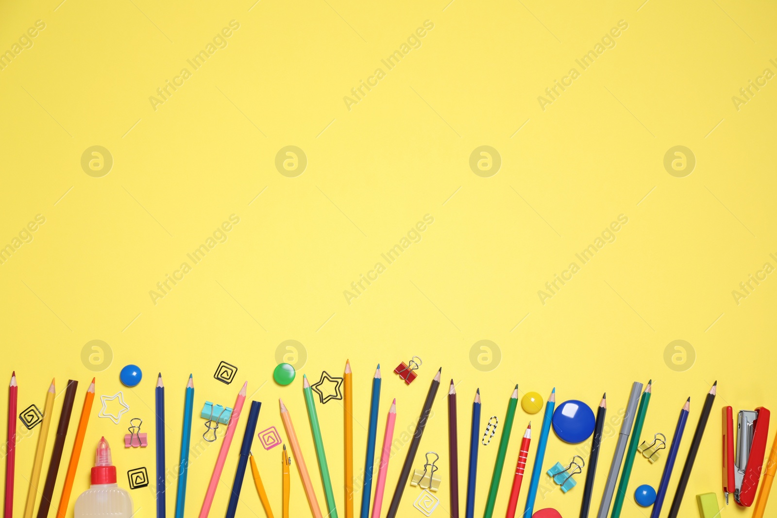 Photo of Bright stationery on yellow background, flat lay. Space for text
