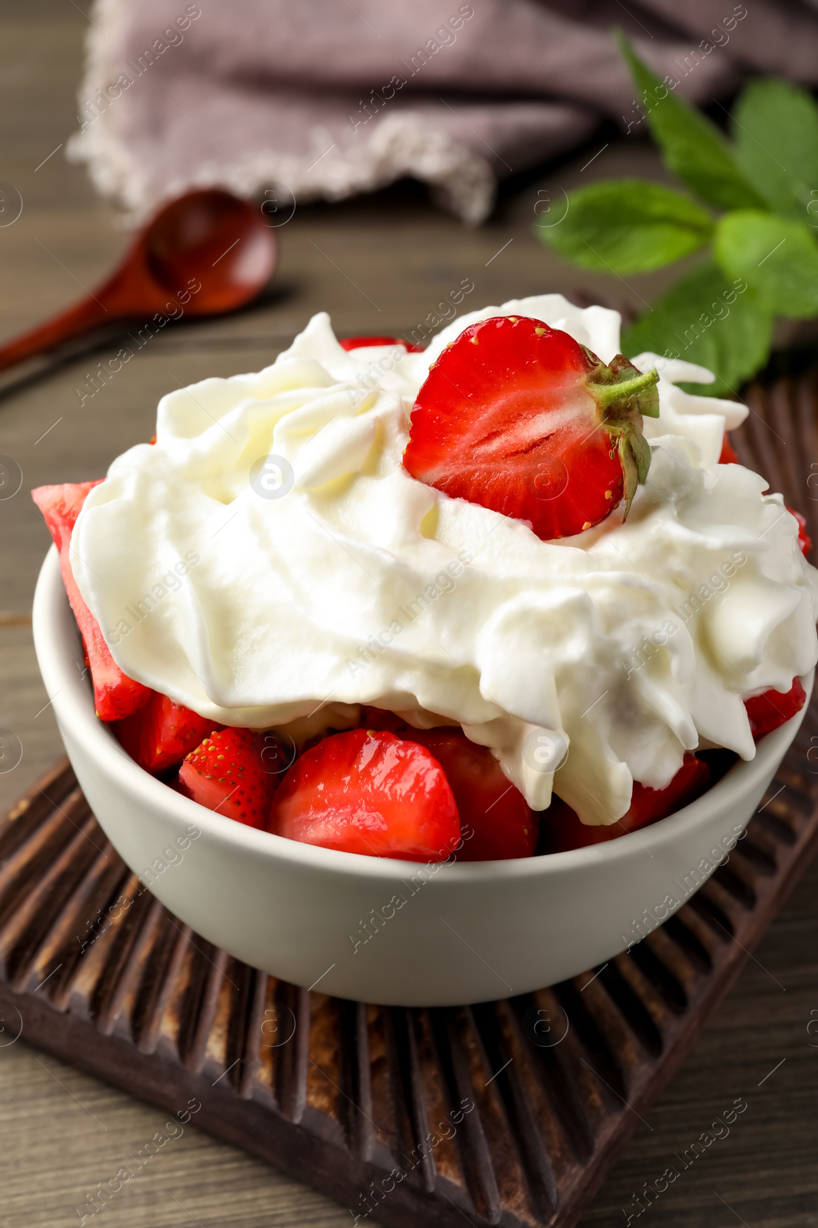 Photo of Delicious strawberries with whipped cream served on wooden table, closeup