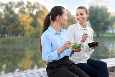 Photo of Business people eating from lunch boxes outdoors. Space for text