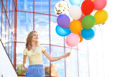 Young woman with colorful balloons outdoors on sunny day