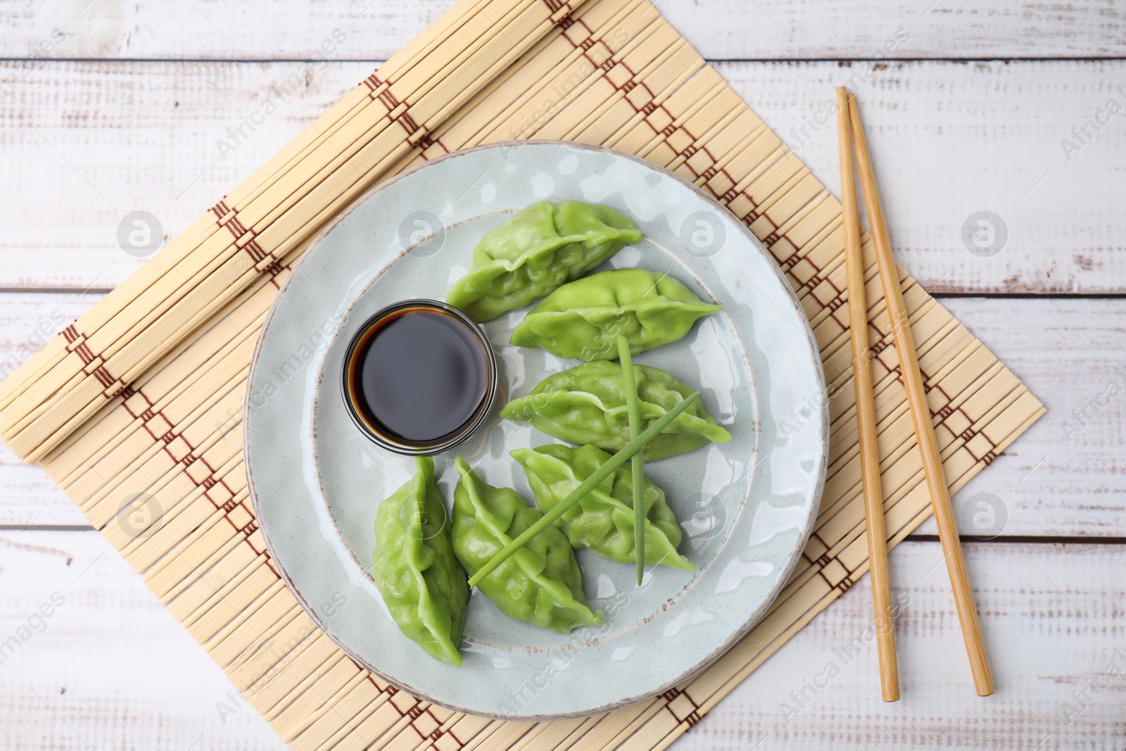 Photo of Delicious green dumplings (gyozas) served on white wooden table, top view
