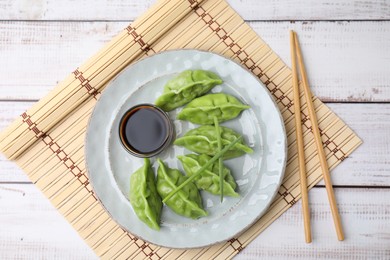 Delicious green dumplings (gyozas) served on white wooden table, top view