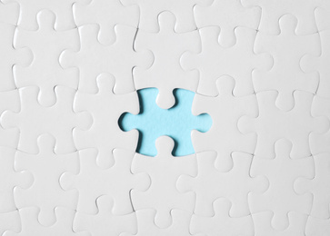 Photo of Blank white puzzle with missing piece on light blue background, top view