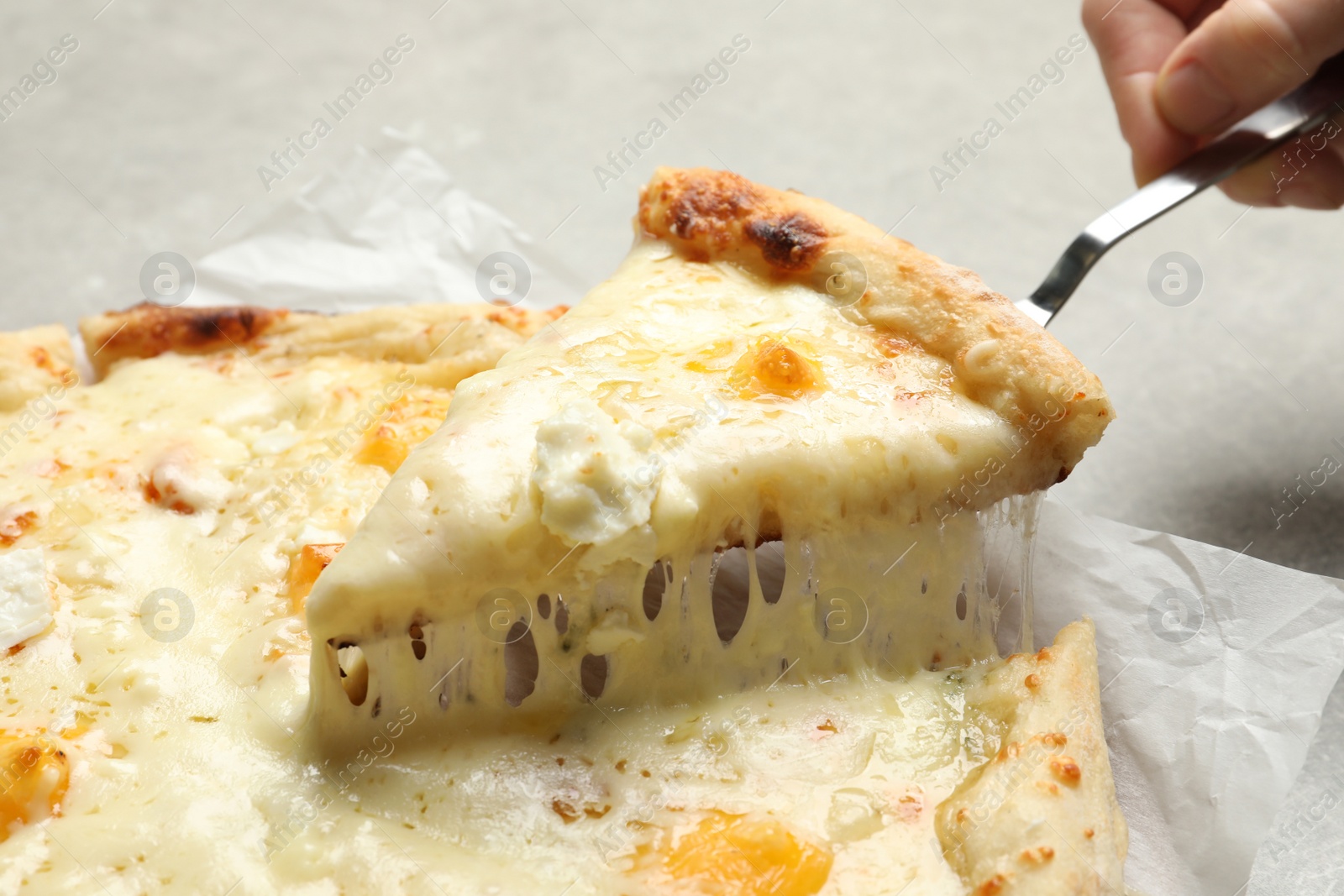 Photo of Woman taking slice of hot cheese pizza Margherita on table, closeup