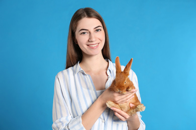 Young woman with adorable rabbit on blue background. Lovely pet