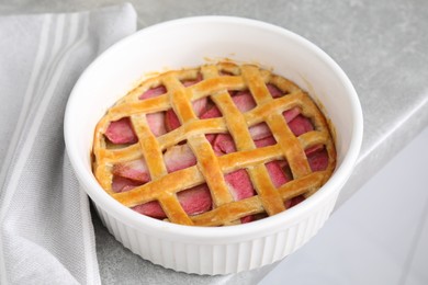 Baking dish with tasty apple pie on light grey table, closeup