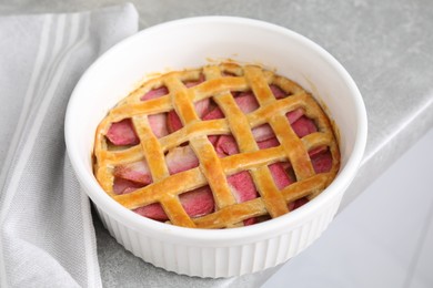 Photo of Baking dish with tasty apple pie on light grey table, closeup