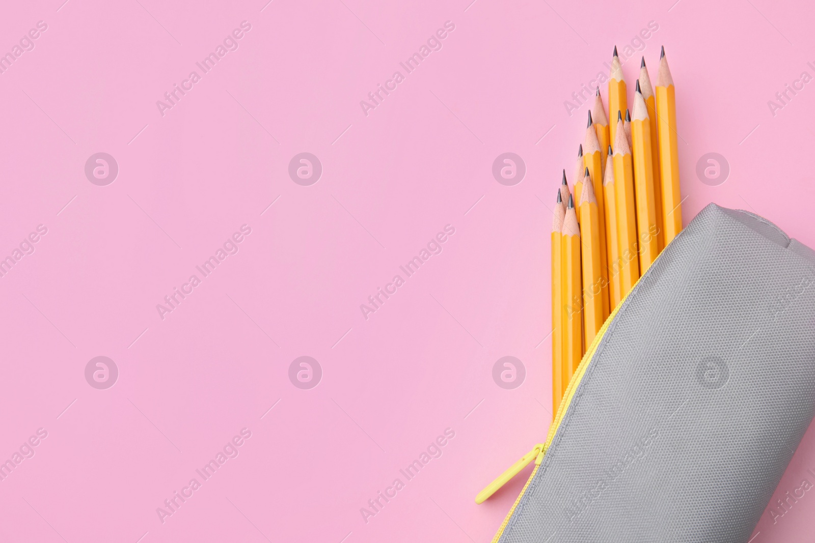 Photo of Many sharp pencils in pencil case on pink background, top view. Space for text
