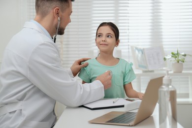 Photo of Pediatrician examining little girl in office at hospital