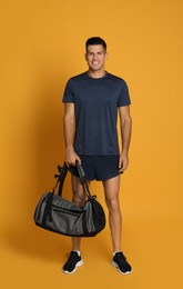 Photo of Handsome man with sports bag on yellow background