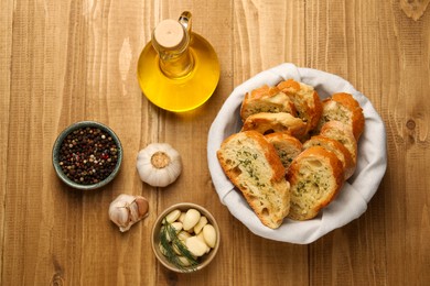 Photo of Tasty baguette with garlic, oil and other spices on wooden table, flat lay