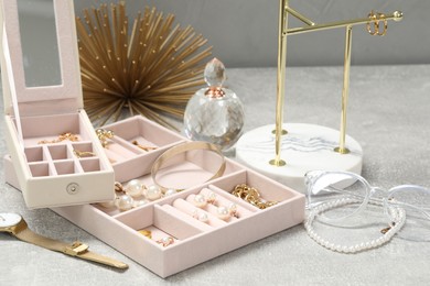 Jewelry boxes with many different accessories, perfume and stand on light grey table