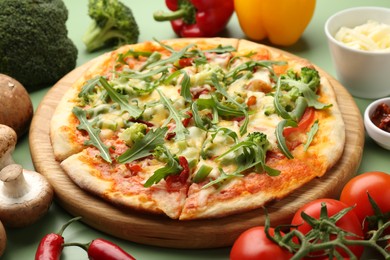 Photo of Delicious vegetarian pizza and products on green table, closeup