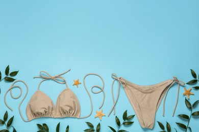 Photo of Stylish bikini, starfishes and leaves on light blue background, flat lay. Space for text
