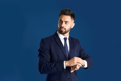 Photo of Portrait of handsome man in business suit checking time on color background