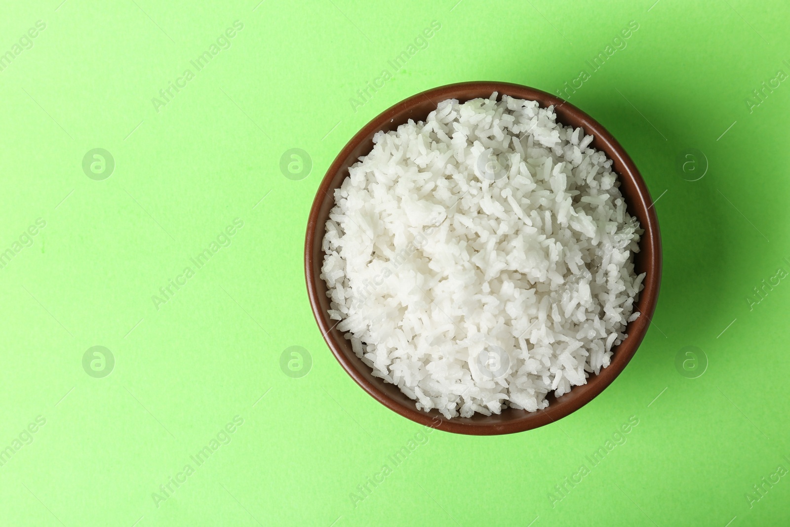 Photo of Bowl of boiled rice on color background, top view with space for text