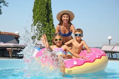 Photo of Woman with her children in swimming pool. Family vacation