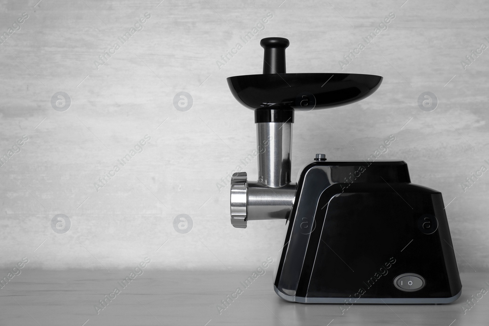 Photo of Modern electric meat grinder on light wooden table. Space for text