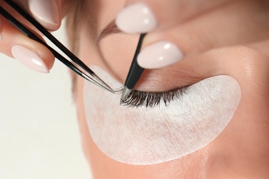 Young woman undergoing eyelash extension procedure, closeup