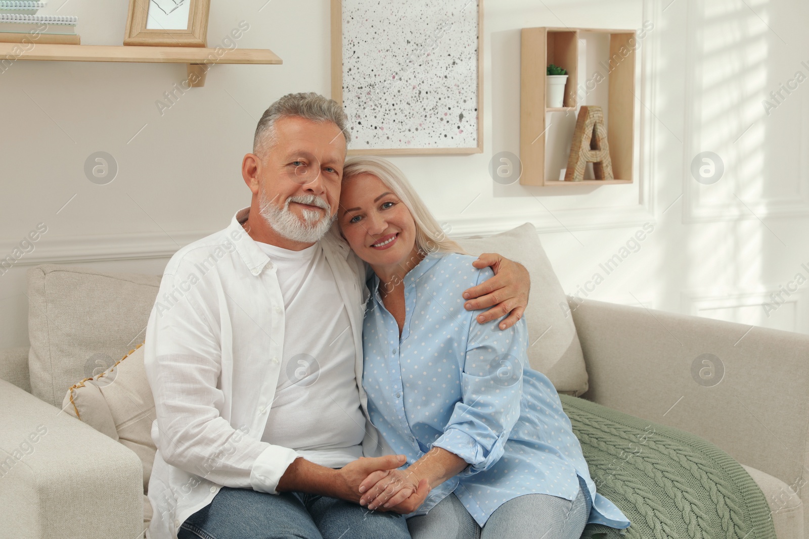 Photo of Happy senior couple sitting on sofa in living room