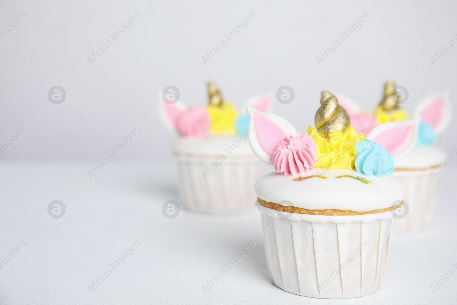 Photo of Cute sweet unicorn cupcakes on white table. Space for text