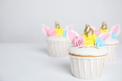 Photo of Cute sweet unicorn cupcakes on white table. Space for text