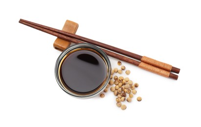 Photo of Tasty soy sauce in bowl, soybeans and chopsticks isolated on white, top view