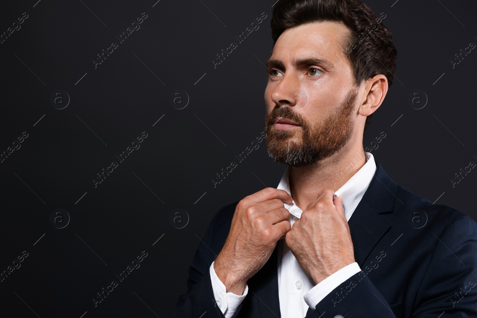 Photo of Portrait of handsome bearded man looking away on black background. Space for text