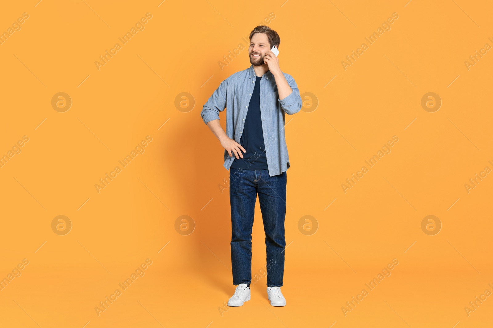 Photo of Man talking on smartphone against orange background