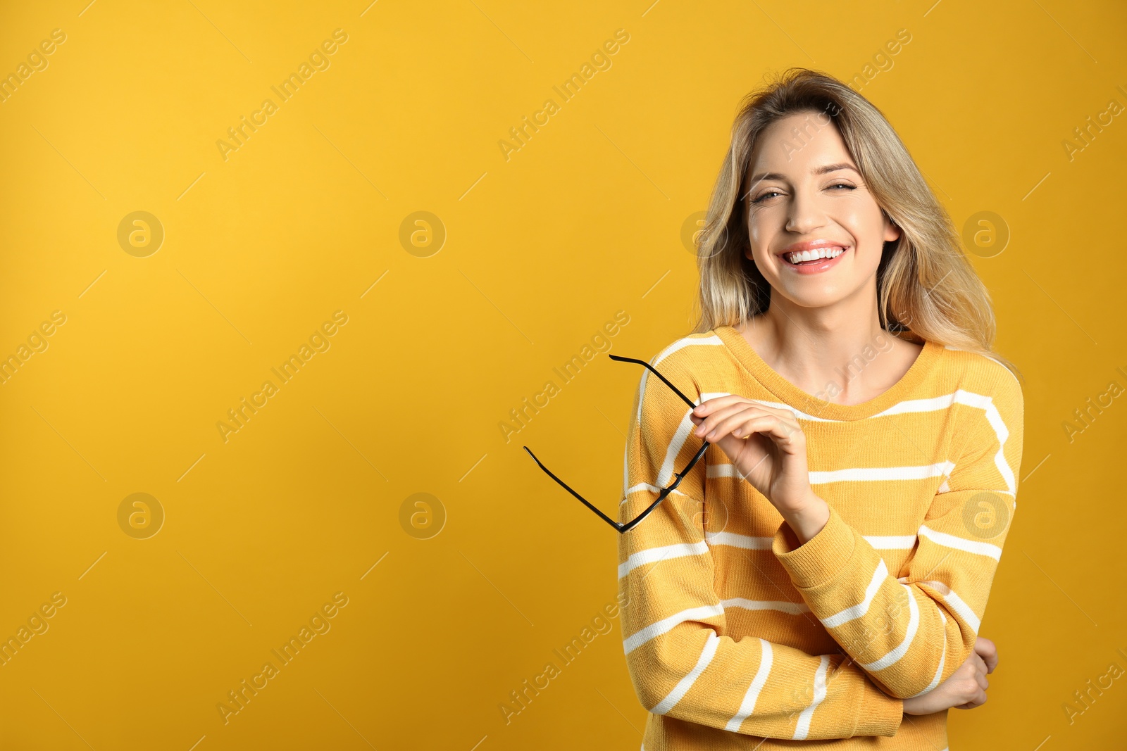 Photo of Portrait of happy young woman with beautiful blonde hair and charming smile on yellow background. Space for text