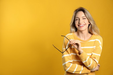 Photo of Portrait of happy young woman with beautiful blonde hair and charming smile on yellow background. Space for text