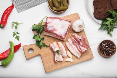 Photo of Flat lay composition with pork fatback, pickled cucumbers and spices on white marble table