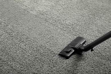 Photo of Removing dirt from grey carpet with modern vacuum cleaner. Space for text