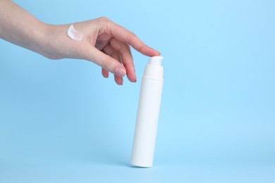 Photo of Woman with cream on light blue background, closeup