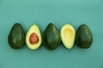 Photo of Tasty whole and cut avocados on turquoise background, flat lay