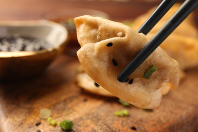 Photo of Taking delicious gyoza (asian dumpling) from wooden board, closeup