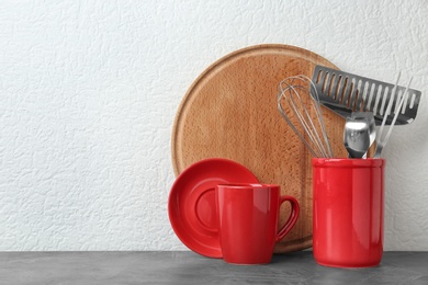 Photo of Set of kitchen utensils in stand on stone table near light wall. Space for text