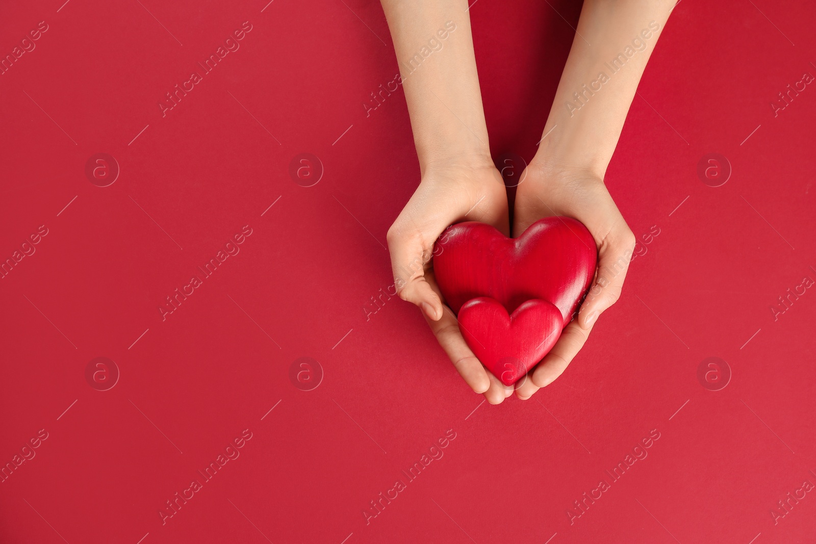 Photo of Woman holding decorative hearts on color background, top view. Space for text