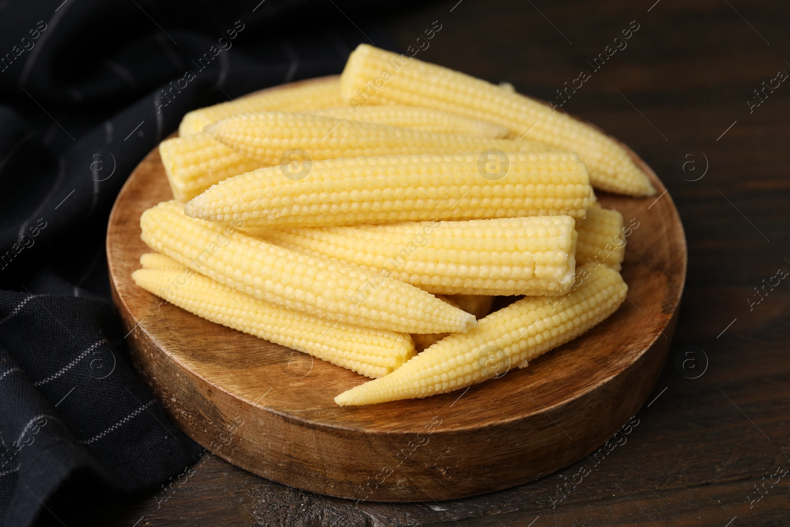 Photo of Tasty fresh yellow baby corns on wooden table