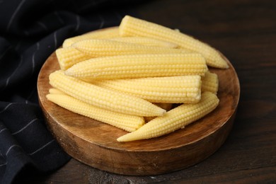 Photo of Tasty fresh yellow baby corns on wooden table